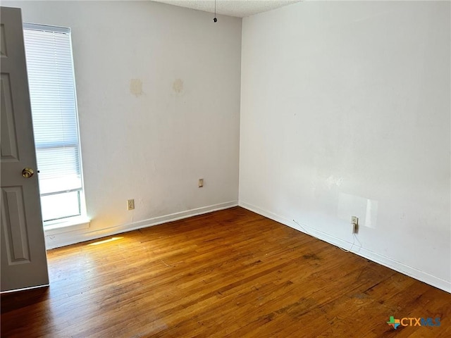 unfurnished room with baseboards and wood finished floors