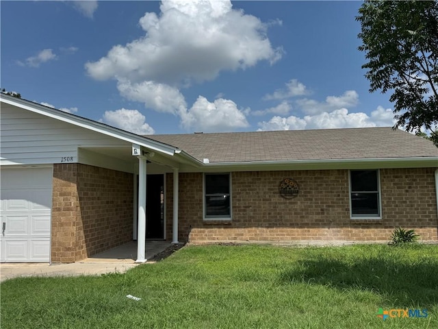 1508 Briar Ln, Killeen, TX 76543 - view of exterior entry with brick siding, a lawn, a shingled roof, and a garage