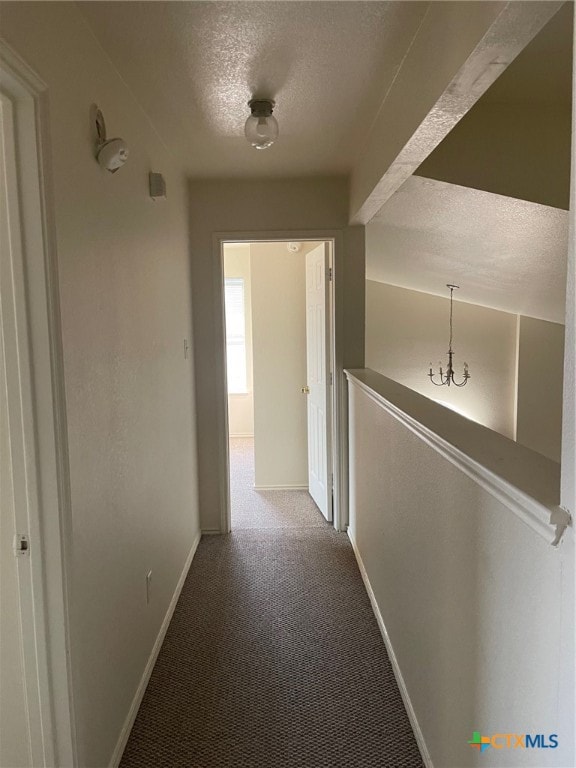 hallway featuring a textured ceiling and carpet floors