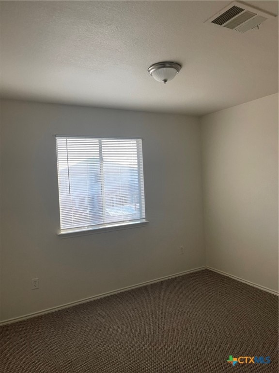 spare room featuring dark colored carpet