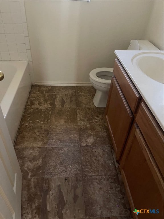 bathroom featuring vanity, a tub to relax in, and toilet