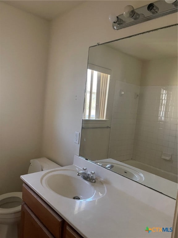 bathroom with a tile shower, vanity, and toilet