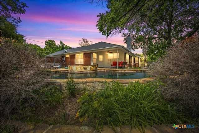 4501 Arrowhead Dr, Temple, TX 76502 - back of property with a chimney, an outdoor pool, a hot tub, and a patio