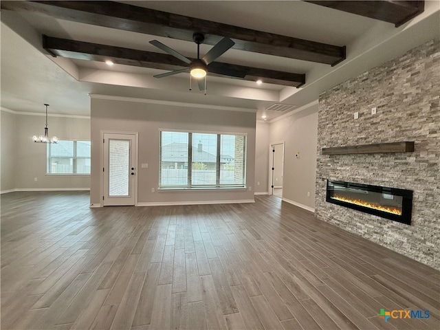 unfurnished living room featuring a stone fireplace, hardwood / wood-style floors, a healthy amount of sunlight, and ceiling fan with notable chandelier