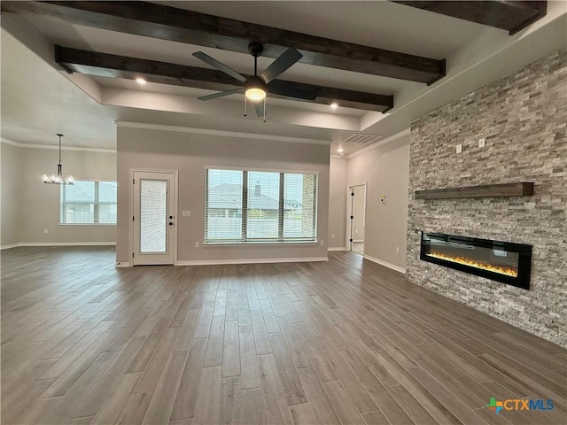 2021 Yarrow Rd, Temple, TX 76502 - unfurnished living room featuring a stone fireplace, a chandelier, healthy amount of natural light, beamed ceiling, and wood finished floors