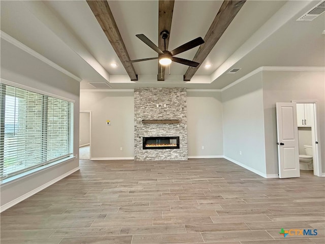 unfurnished living room with light wood-type flooring, ceiling fan, crown molding, beamed ceiling, and a fireplace