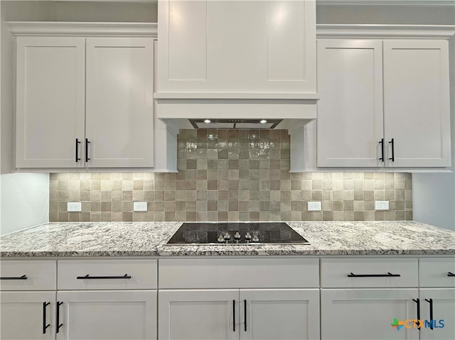 kitchen featuring tasteful backsplash, white cabinetry, and black electric stovetop