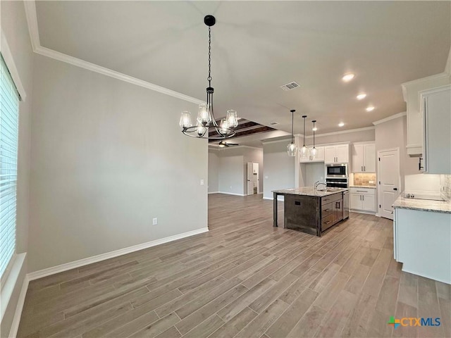 2021 Yarrow Rd, Temple, TX 76502 - kitchen featuring a chandelier, open floor plan, stainless steel microwave, ornamental molding, and light wood finished floors