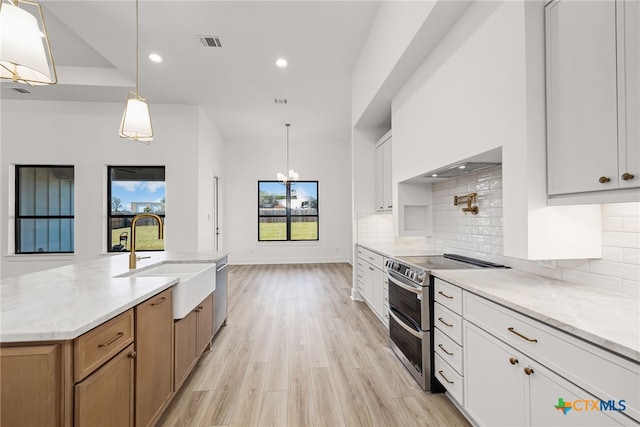 kitchen featuring light hardwood / wood-style floors, sink, white cabinetry, appliances with stainless steel finishes, and decorative light fixtures