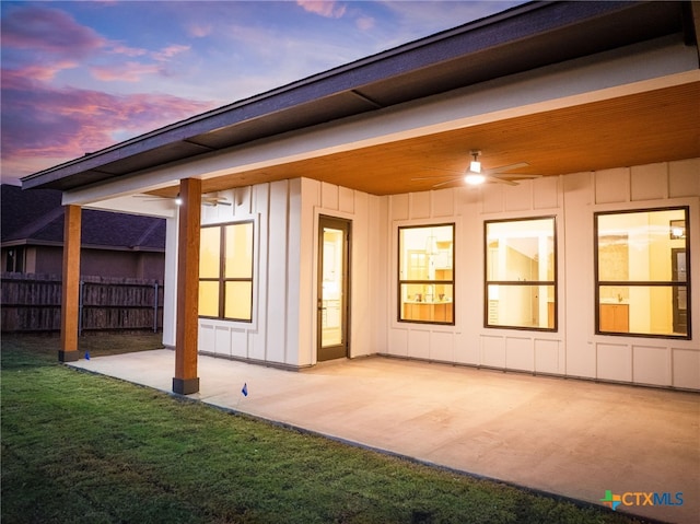 back house at dusk featuring ceiling fan, a yard, and a patio