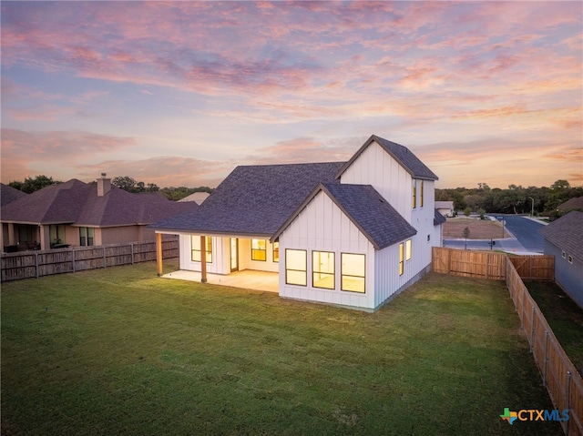 back house at dusk featuring a patio area and a yard