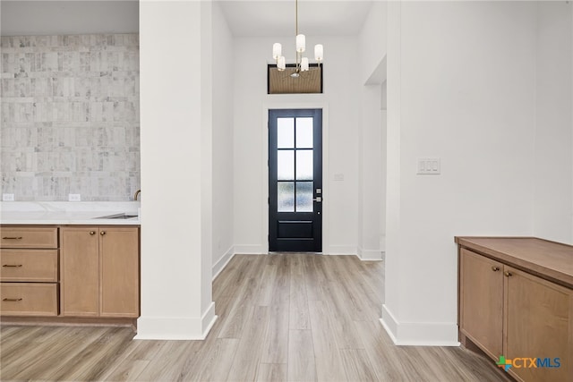 entryway featuring light hardwood / wood-style floors, a chandelier, sink, and tile walls