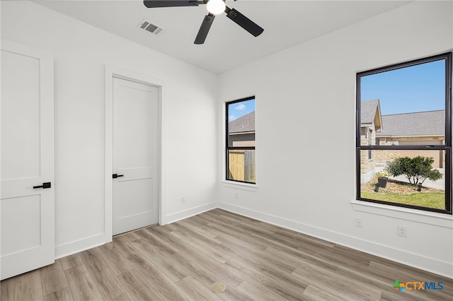 unfurnished bedroom featuring ceiling fan, multiple windows, and light wood-type flooring