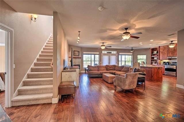 living room with a textured ceiling, dark wood-type flooring, and ceiling fan