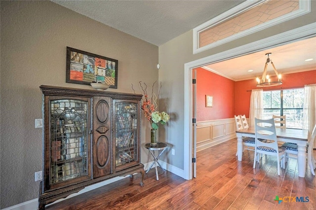 entryway with a notable chandelier, ornamental molding, a textured ceiling, and hardwood / wood-style flooring