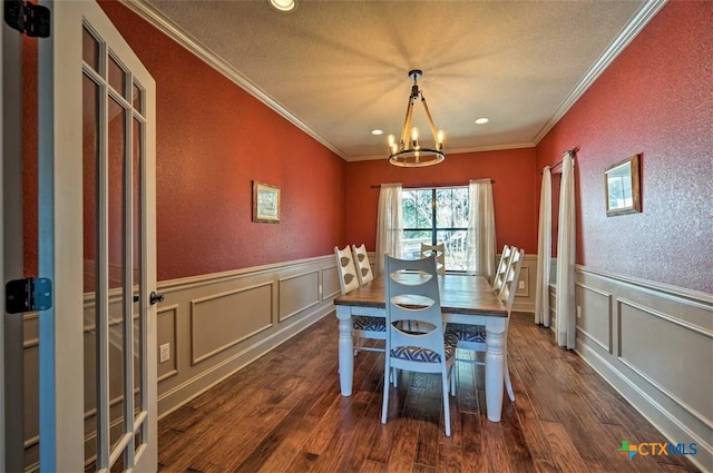 dining room featuring dark hardwood / wood-style flooring, a textured ceiling, a chandelier, and ornamental molding