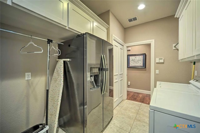 clothes washing area with washer and dryer, light tile patterned floors, and cabinets