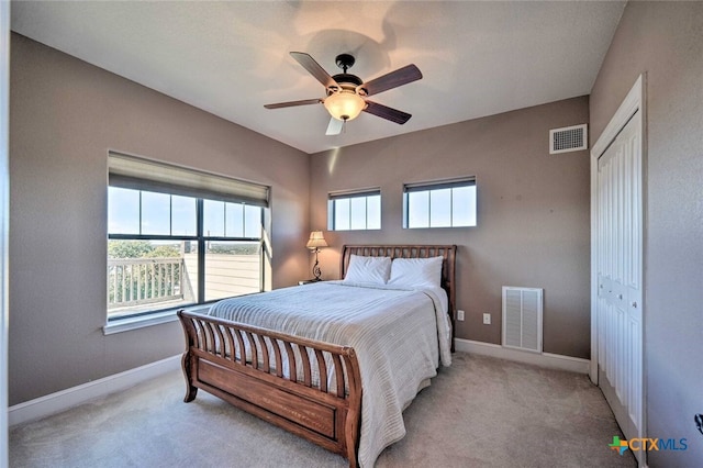 bedroom featuring light colored carpet, ceiling fan, and a closet