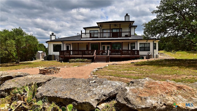 rear view of house with a lawn, a fire pit, and a balcony