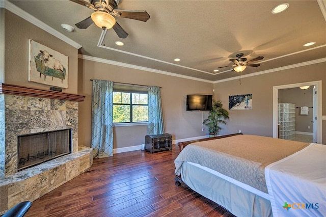 bedroom featuring ceiling fan, dark hardwood / wood-style flooring, ornamental molding, and a fireplace