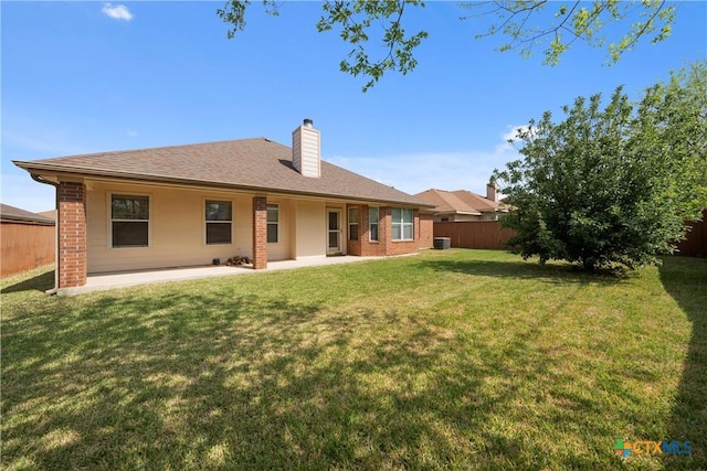 rear view of house featuring a lawn, central air condition unit, and a patio area