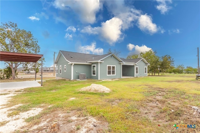 rear view of property featuring central AC, a yard, and a carport