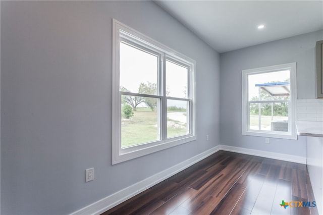 unfurnished room featuring dark hardwood / wood-style floors and a healthy amount of sunlight