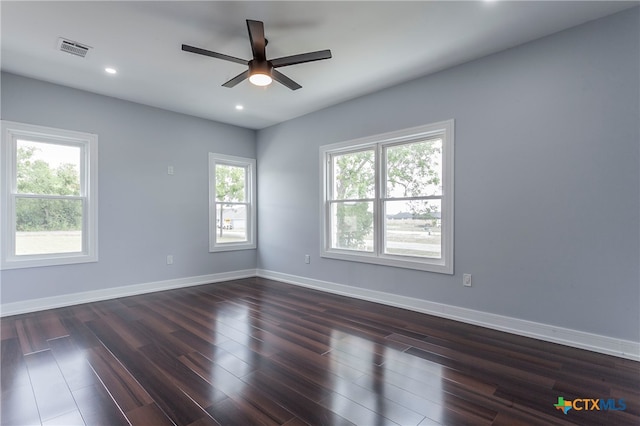 spare room with dark wood-type flooring, a wealth of natural light, and ceiling fan