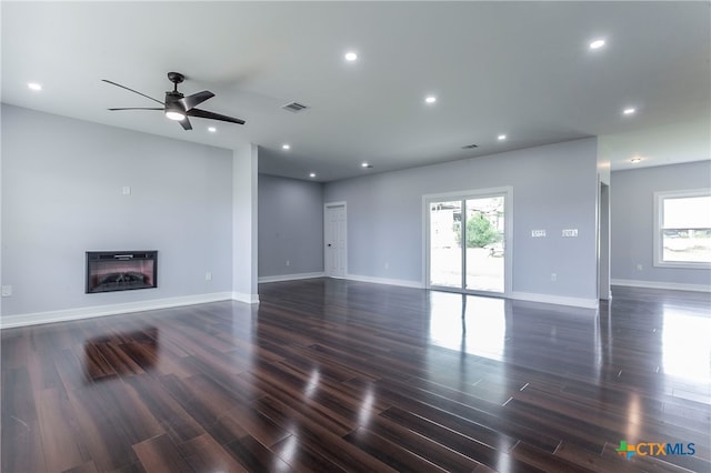 unfurnished living room featuring a wealth of natural light, ceiling fan, and dark hardwood / wood-style flooring