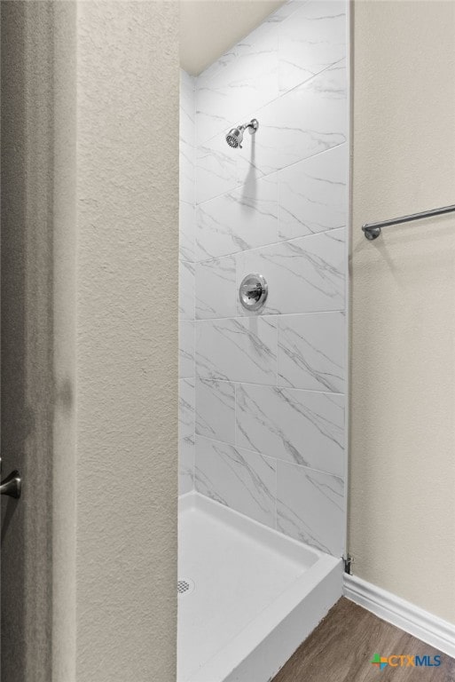 bathroom with hardwood / wood-style floors and a tile shower