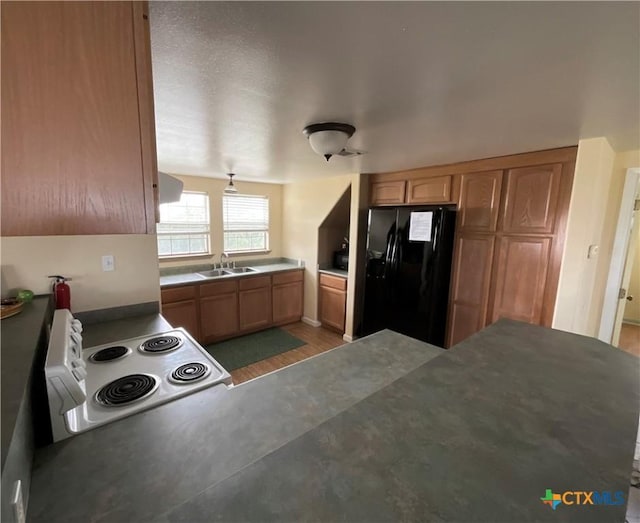364 N Blackburn Ave, Port Lavaca, TX 77979 - kitchen featuring black fridge with ice dispenser, white electric range oven, a sink, ventilation hood, and light wood-style floors