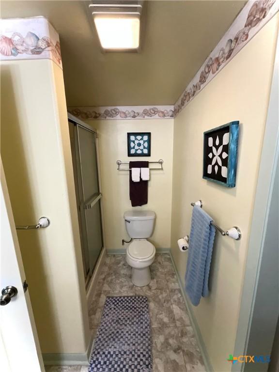 364 N Blackburn Ave, Port Lavaca, TX 77979 - bathroom featuring toilet, a shower with shower door, and baseboards