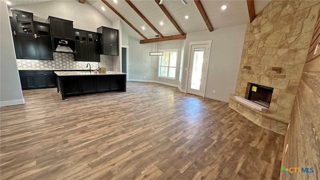 kitchen featuring wood-type flooring, hanging light fixtures, sink, an island with sink, and high vaulted ceiling