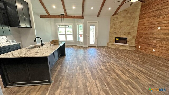 kitchen with a center island with sink, sink, dark hardwood / wood-style flooring, pendant lighting, and lofted ceiling with beams