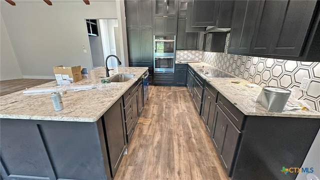 kitchen with hardwood / wood-style floors, sink, double oven, and light stone countertops