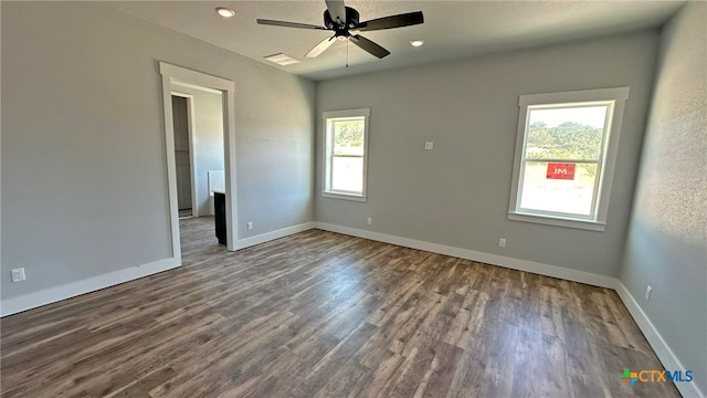 unfurnished room featuring a wealth of natural light, dark hardwood / wood-style floors, and ceiling fan