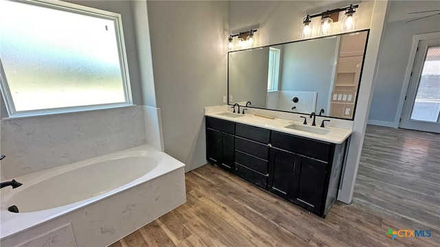 bathroom with a bath, wood-type flooring, a healthy amount of sunlight, and vanity