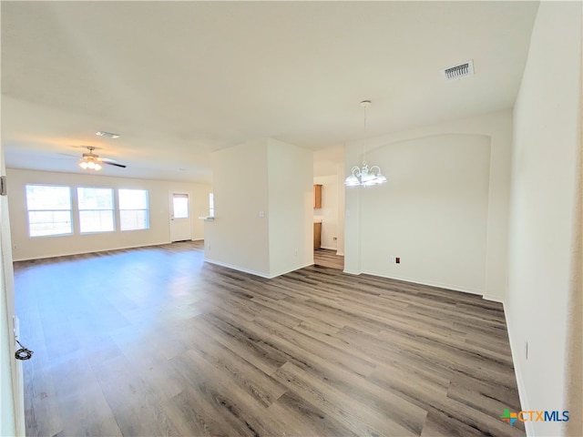 empty room featuring ceiling fan with notable chandelier and hardwood / wood-style flooring