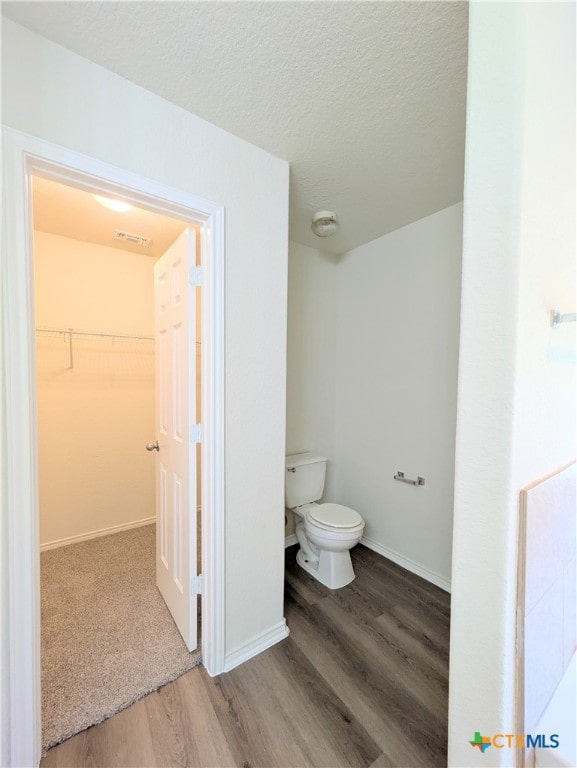 bathroom featuring hardwood / wood-style flooring, toilet, and a textured ceiling