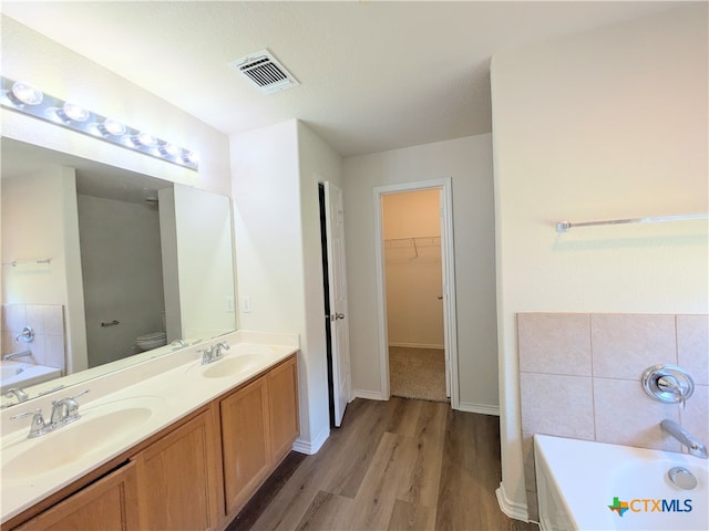 bathroom with a bathing tub, vanity, toilet, and wood-type flooring