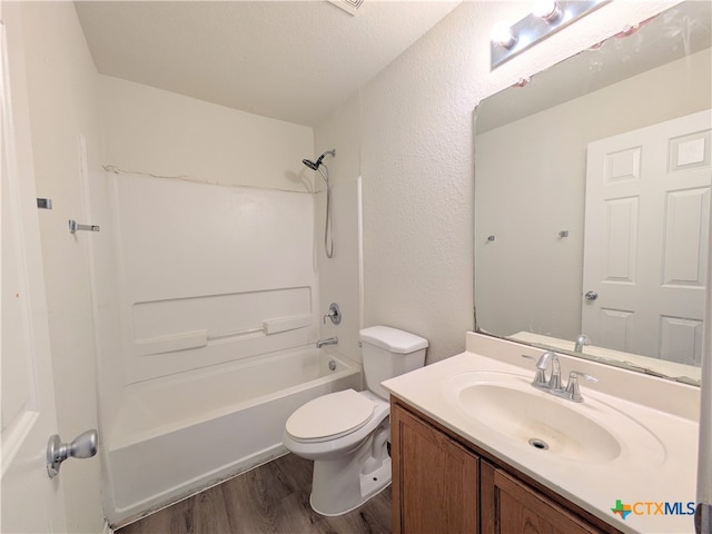 full bathroom featuring bathing tub / shower combination, wood-type flooring, a textured ceiling, toilet, and vanity