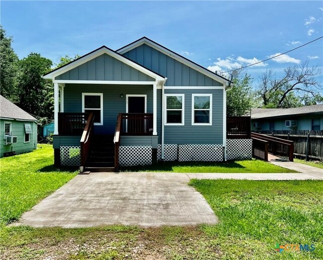 313 Rorem Ave, Palacios, TX 77465 - bungalow featuring board and batten siding, covered porch, a patio area, cooling unit, and a front yard