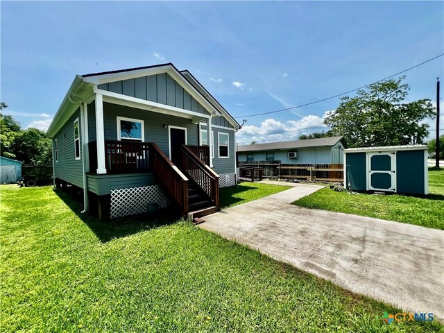 313 Rorem Ave, Palacios, TX 77465 - view of front facade featuring a front lawn, an outdoor structure, covered porch, a shed, and board and batten siding