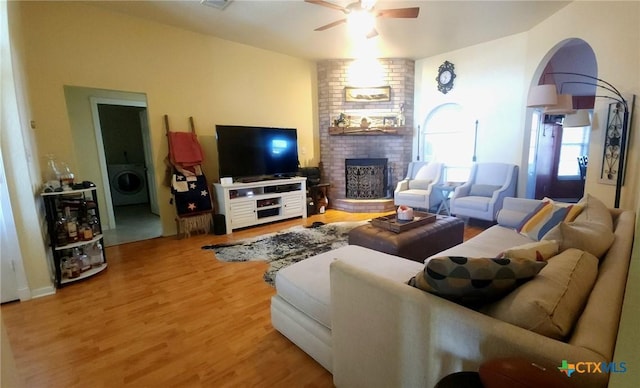 living room with washer / clothes dryer, a brick fireplace, hardwood / wood-style flooring, and ceiling fan