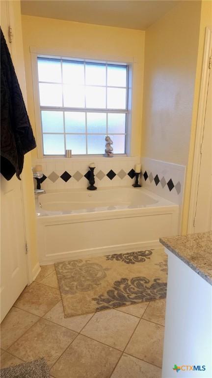 bathroom featuring tile patterned floors, a bathing tub, and vanity