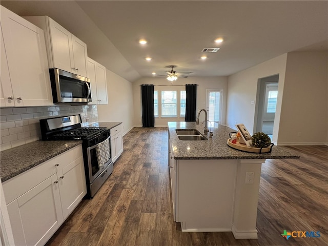 kitchen with stainless steel appliances, white cabinetry, dark hardwood / wood-style flooring, sink, and a kitchen island with sink