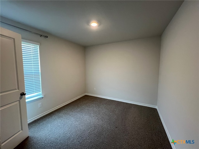 spare room featuring dark carpet