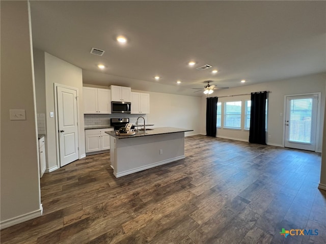 kitchen with white cabinetry, appliances with stainless steel finishes, dark hardwood / wood-style floors, ceiling fan, and a kitchen island with sink