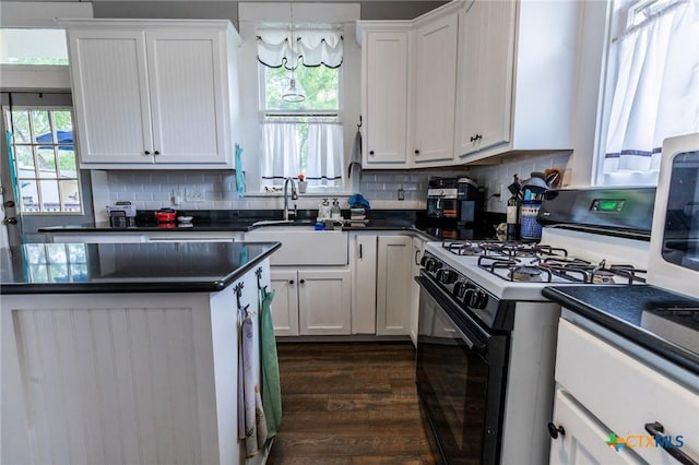 225 W Humphreys St, Seguin, TX 78155 - kitchen featuring range with gas stovetop, dark countertops, a sink, and white cabinetry