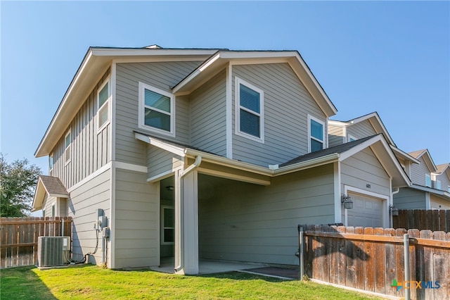 back of house featuring central AC unit, a yard, and a garage